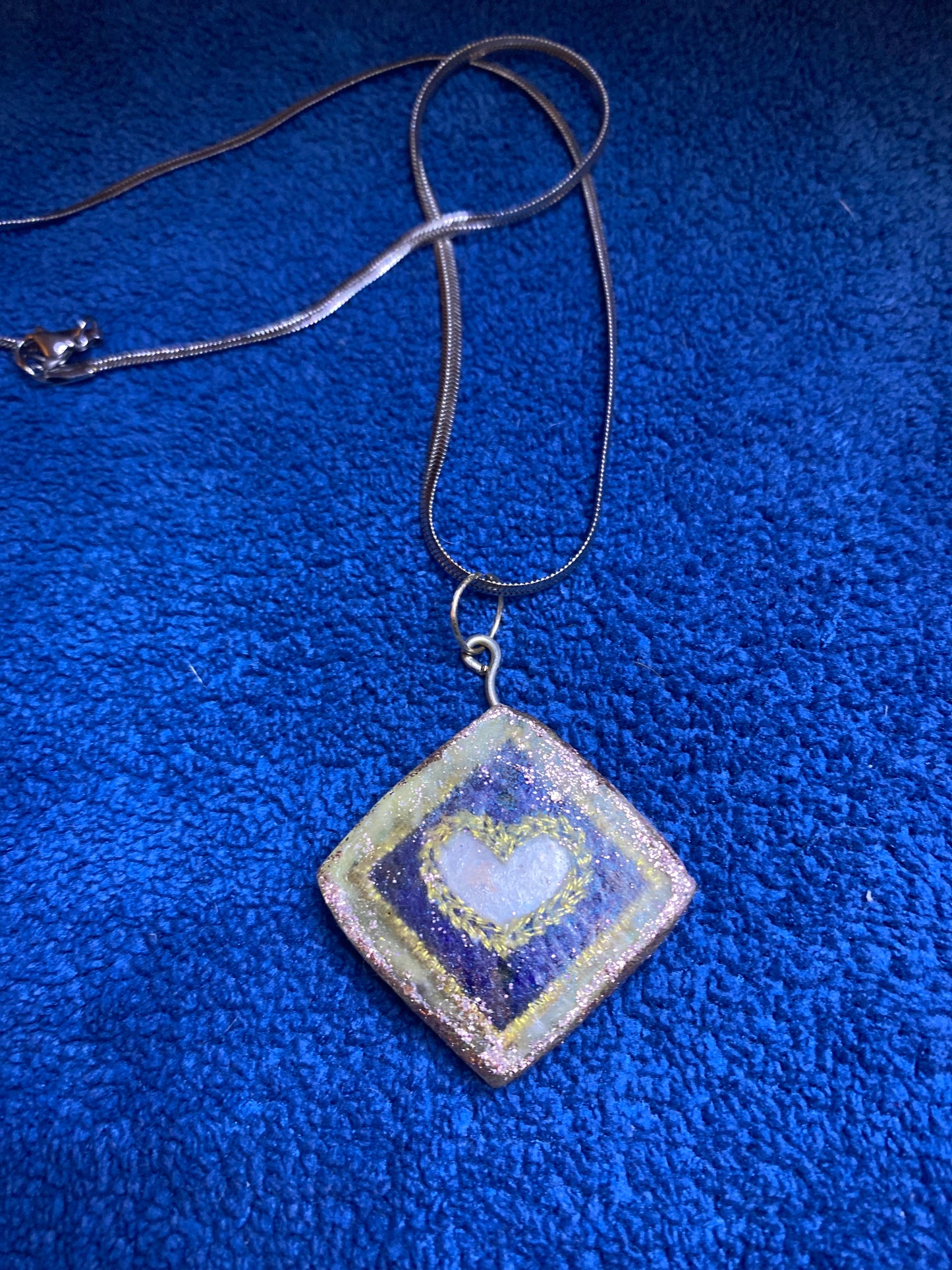 A handmade pendant with a silver colored chain.