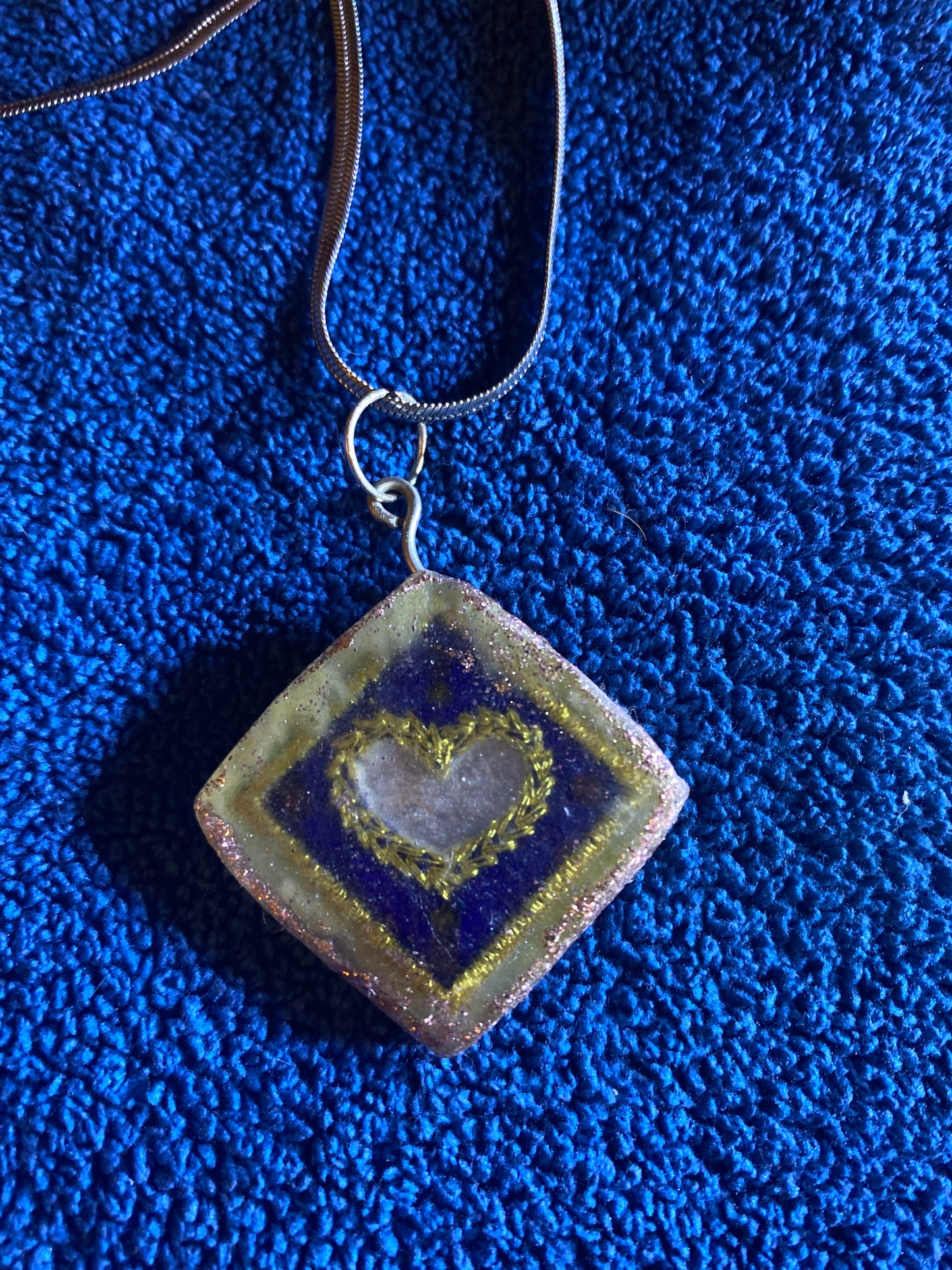 A handmade pendant with a silver colored chain.