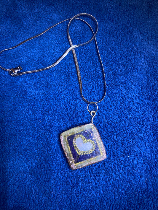 A handmade pendant with a silver colored chain.